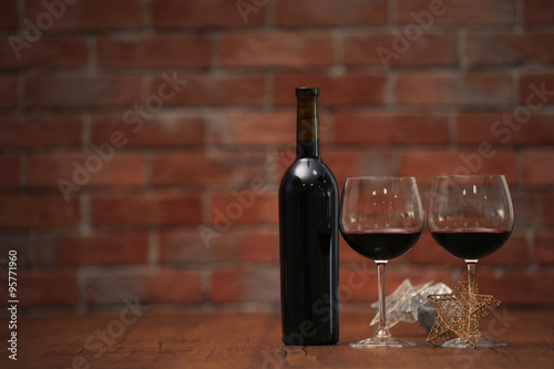 Red wine and Christmas ornaments on wooden table on wall brick background
