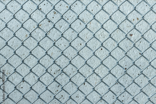Wire fence with cement wall background.