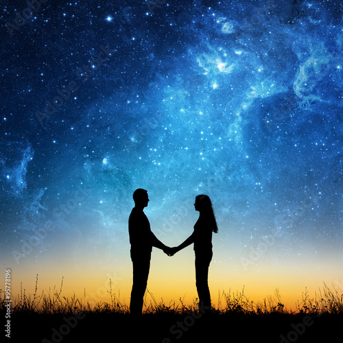Silhouette of young couple under stars. The concept on the theme of love. Elements of this image furnished by NASA.