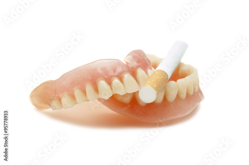 Dentures with a cigarette on a white background