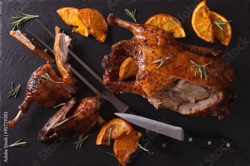 Cutting the roast duck and oranges on a slate board. Horizontal top view
