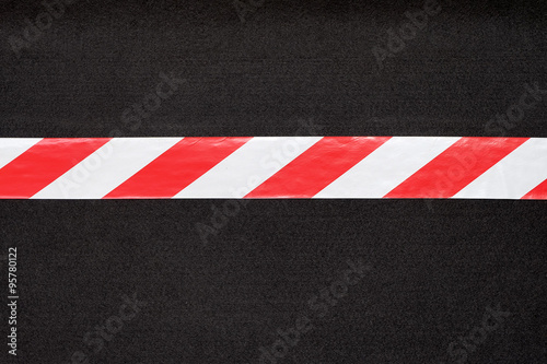 Red and white warning tape on the black carpet. © Phawat