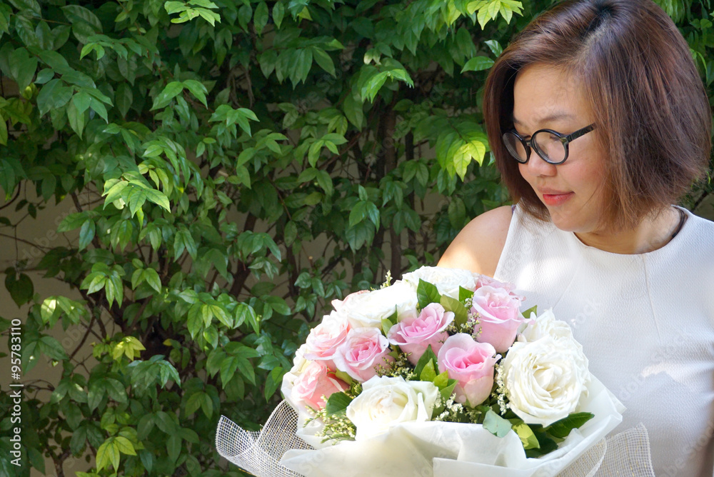 Asian lady wearing glasses smiling and holding beautiful bouquet Asian lady wearing glasses smiling and holding beautiful bouquet