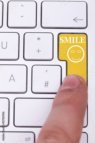 Finger pushing smile button on keyboard