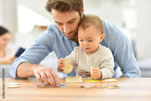 Man playing with baby girl at home photo