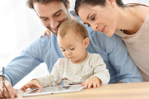 Parents with baby girl playing with digital tablet