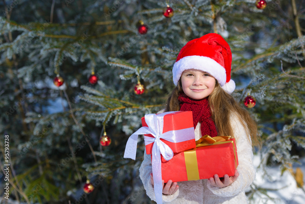 Adorable  little girl with christmas gifts in winter forest
