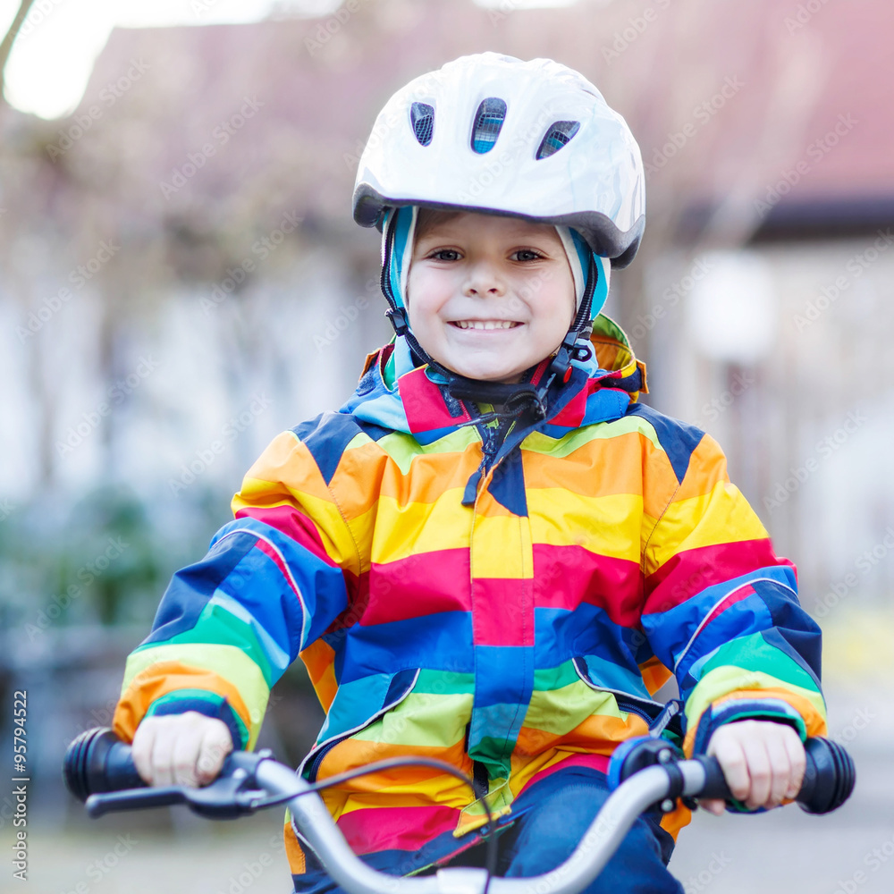 kid boy in safety helmet and colorful raincoat riding bike, outd kid boy in safety helmet and colorful raincoat riding bike, outd