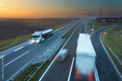 Many trucks in motion blur on the motorway at sunset