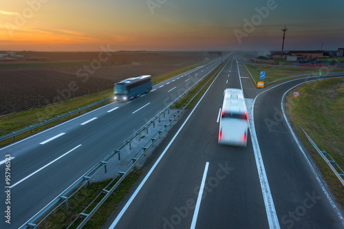 Two buses in motion blur on the highway at sunset