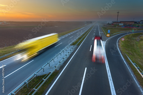 Two trucks in motion blur on the highway at sunset