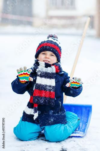 Little boy playing with snow in winter, outdoors.