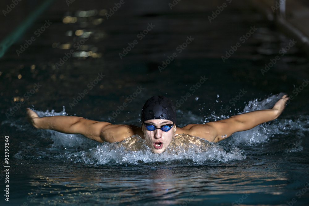 dynamic and fit swimmer in cap breathing performing the butterfl