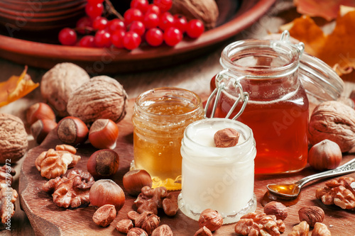 Three types of honey with walnuts and hazelnuts on the autumn ba