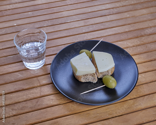 Cretan barley rusks with local gruyere cheese, green olives and a glass of raki photo