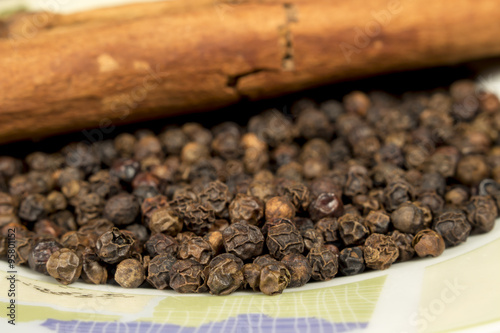 Black pepper grains and cinnamon on decorated dish