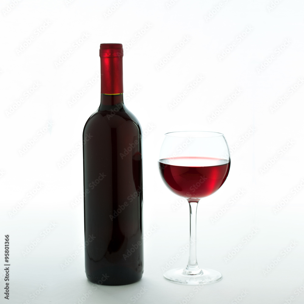 Glass and bottle of red wine unusually on white background. Glass and bottle of red wine unusually on white background.