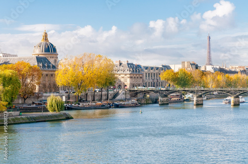 The Seine, the French Academy, the Pont des Arts and the Eiffel tower seen from the Pont Neuf in Paris. Houseboats moored at the dock. photo