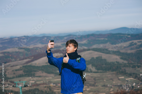 Young hipster taking photo by smart-phone on the peak of mountai © jul14ka