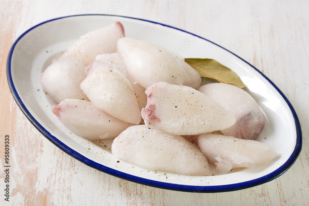 frozen squids in dish on white wooden background frozen squids in dish on white wooden background