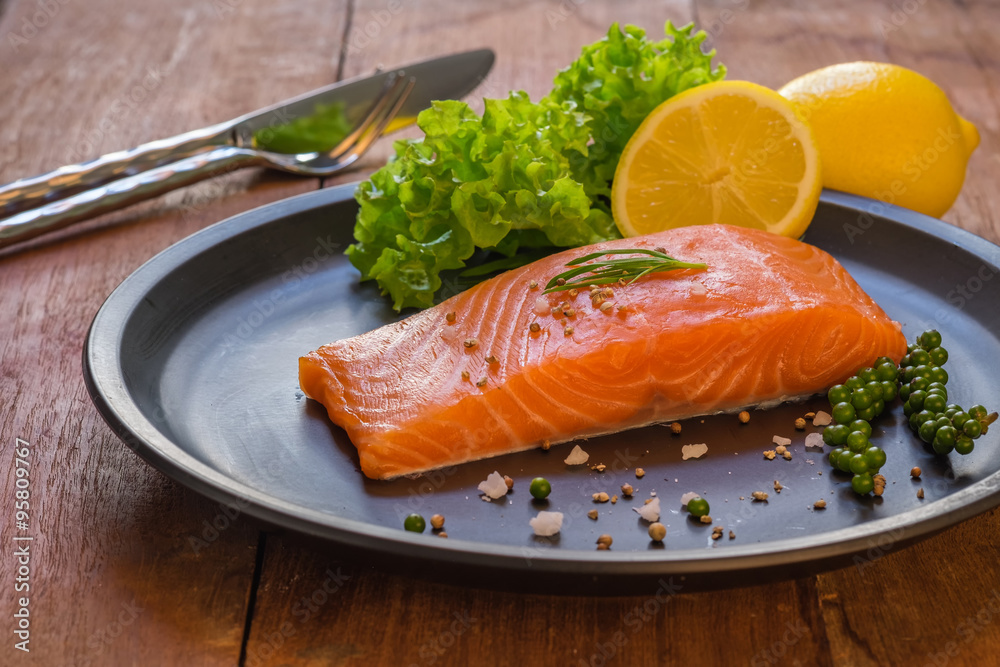 Fresh salmon with lemon on black dish. Fresh salmon with lemon on black dish.