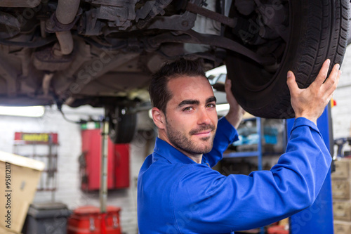 Young attractive mechanic working on a car at the garage