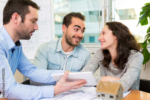 Young attractive people meeting real estate agent at the office