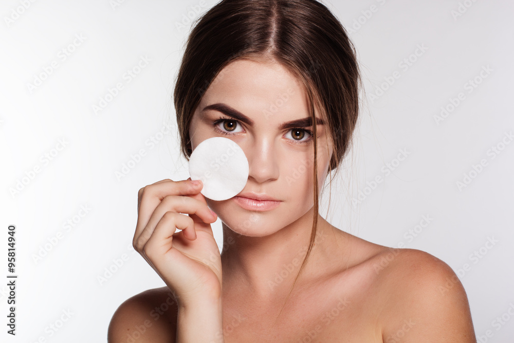 Pretty young girl is cleaning skin with cotton disc Pretty young girl is cleaning skin with cotton disc