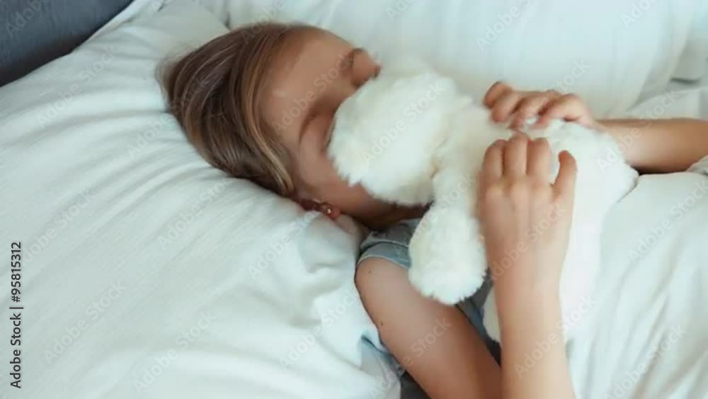 Girl child playing with teddy bear and hugging toy in a bed. Top view Girl child playing with teddy bear and hugging toy in a bed. Top view