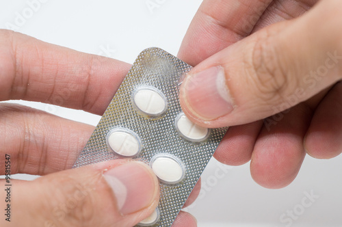 Close up of man's hand taking out pills from blister pack photo