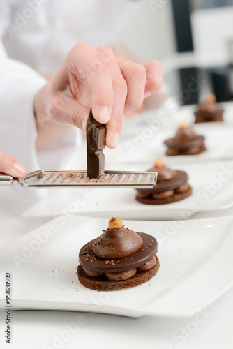 close up of professional pastry cook hands preparing chocolate dessert in restaurant kitchen
