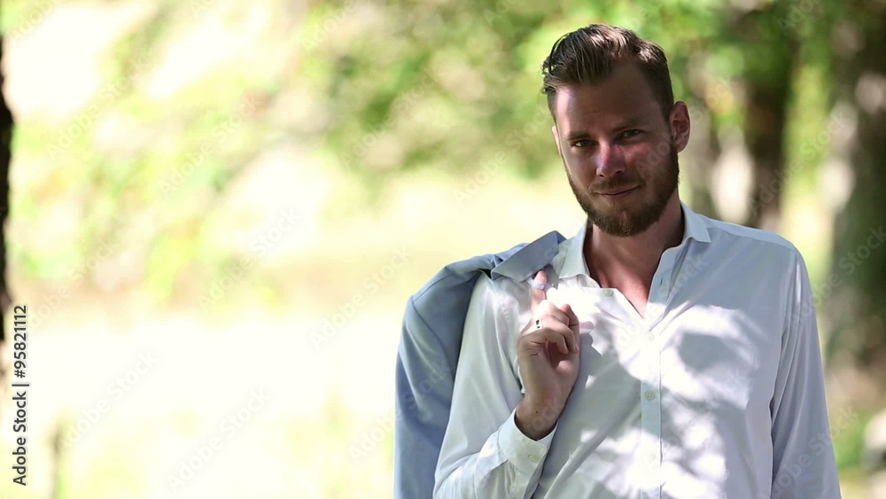 An attractive man wearing white shirt and blazer standing outside on a sunny summer day. An attractive man wearing white shirt and blazer standing outside on a sunny summer day.