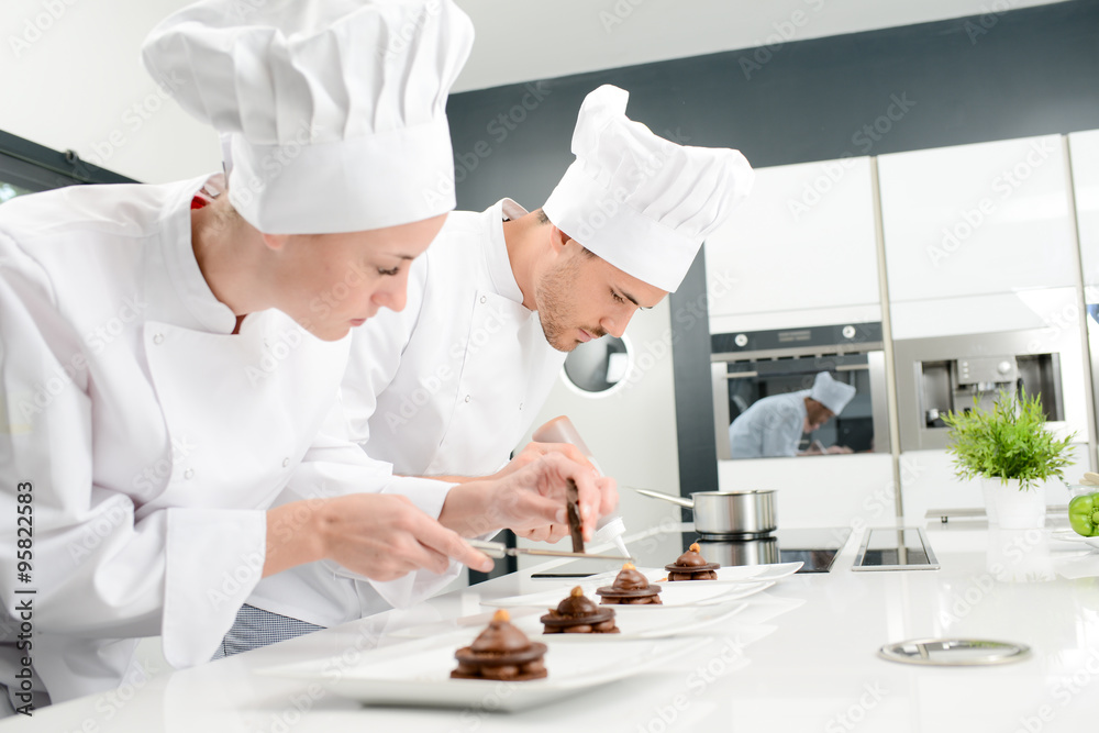 pastry cook professional team man and woman in restaurant kitchen preparing a chocolate dessert - obrazy, fototapety, plakaty 