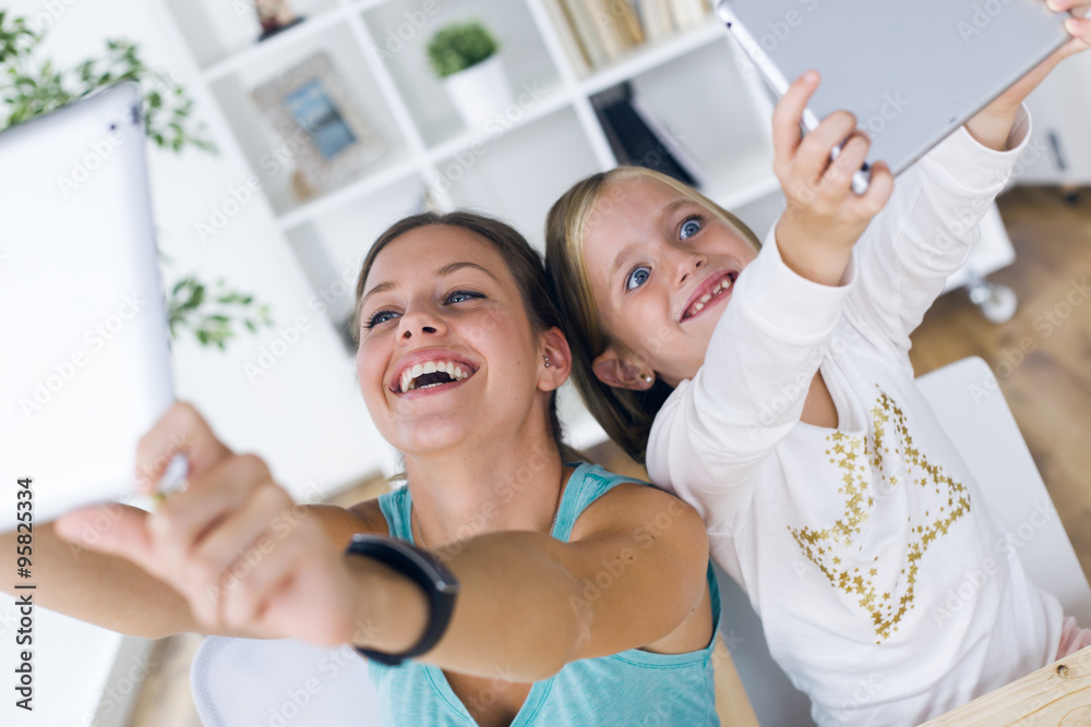 Young mother and daughter playing with digital tablet at home. Young mother and daughter playing with digital tablet at home.