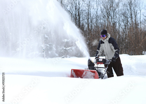 A man works snow blowing machine