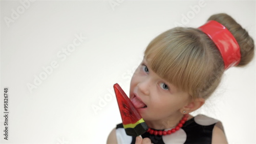 Kid girl with lollipop showing tongue photo