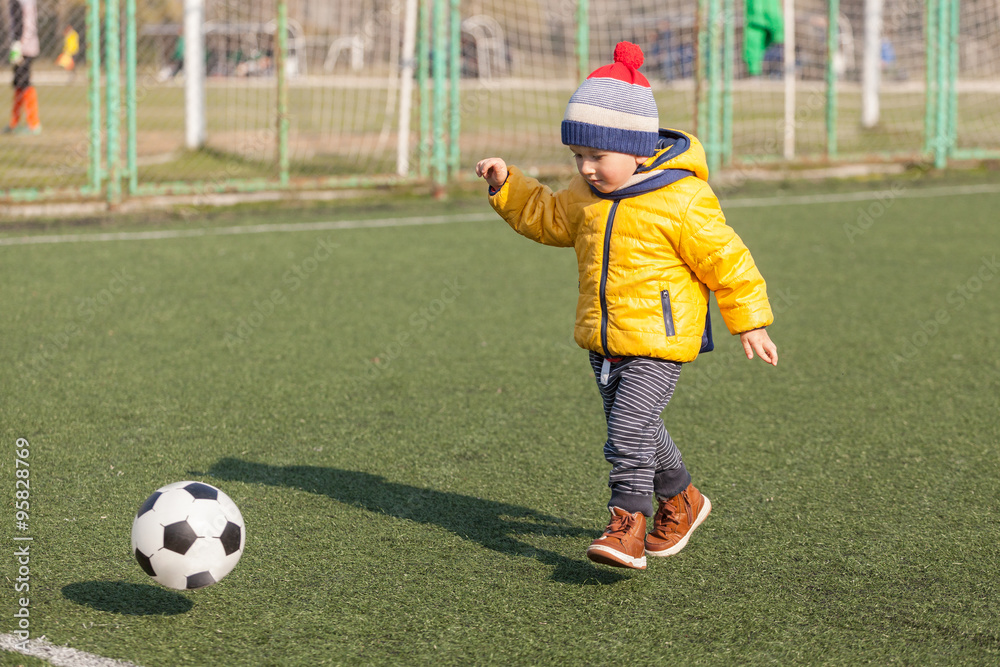 Obraz premium little boy playing with soccer or football ball. sports for exercise and activity.