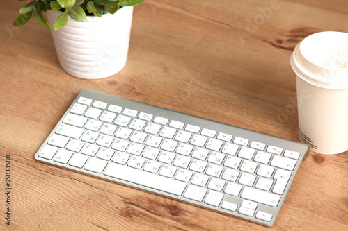 Modern aluminum keyboard on the wooden table in the office