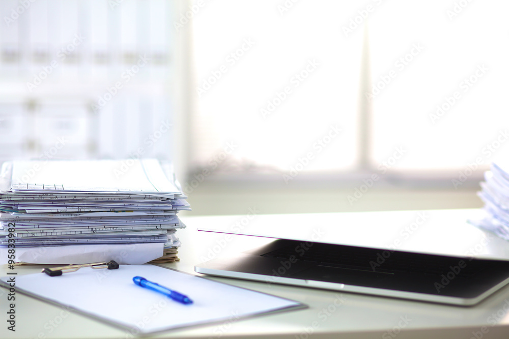 Laptop with stack of folders on table on white background Laptop with stack of folders on table on white background