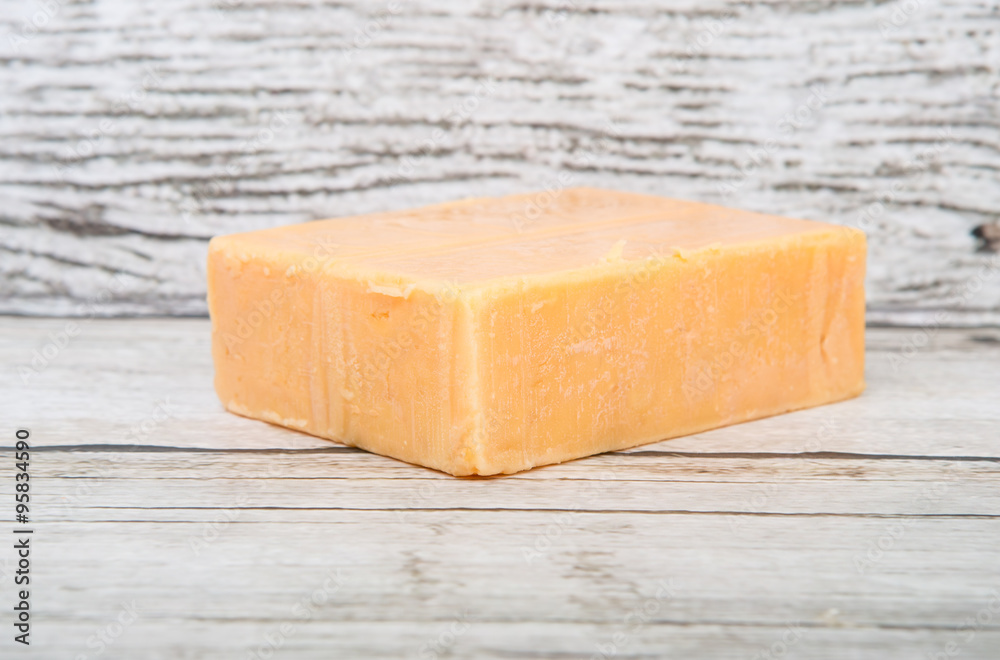 A block of cheddar cheese over wooden background