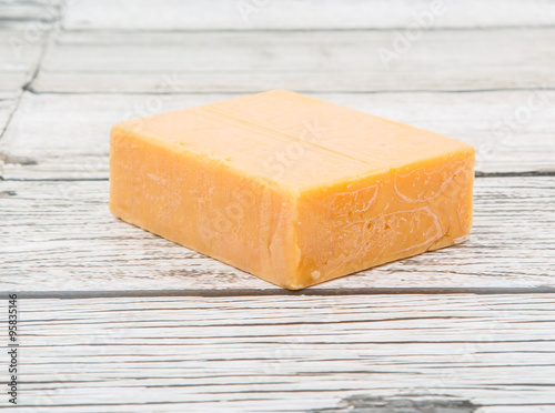 A block of cheddar cheese over wooden background