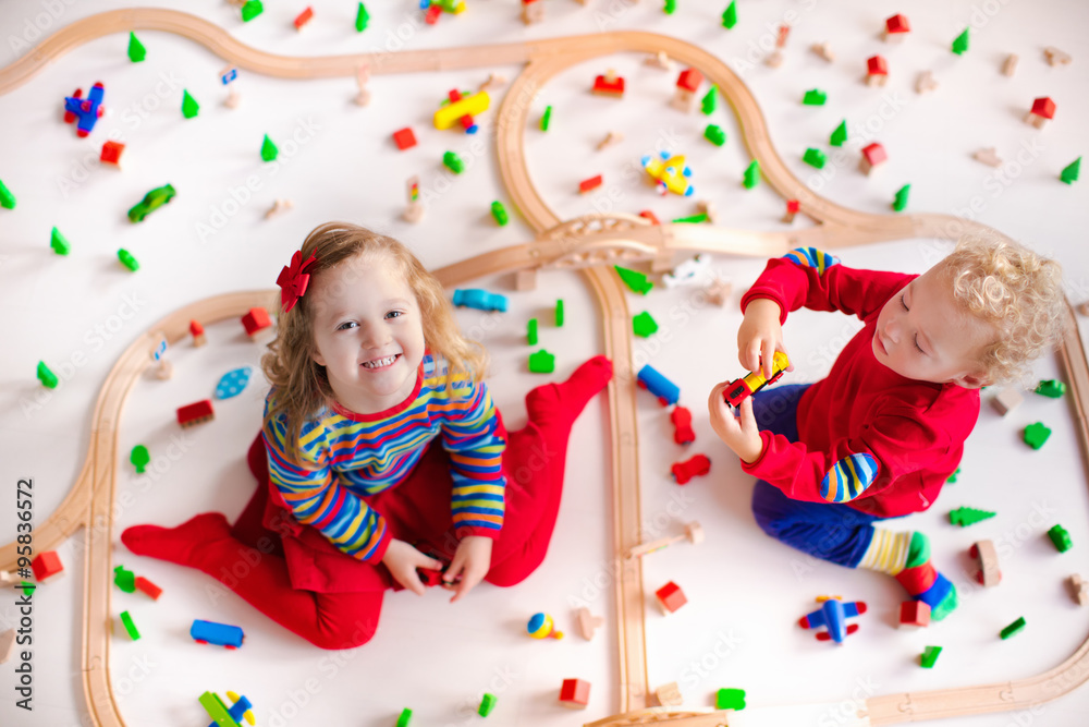 Fototapeta premium Kids playing with wooden train set