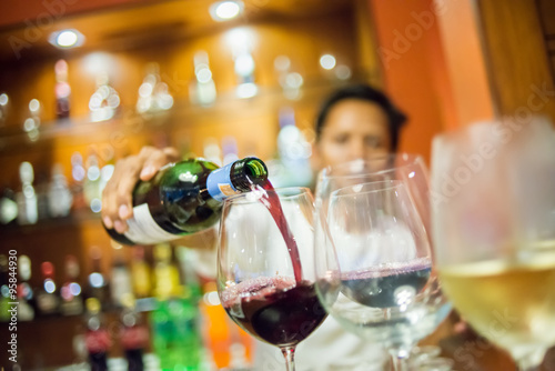 Blurry Man pouring red wine into glass with white wine foregroun