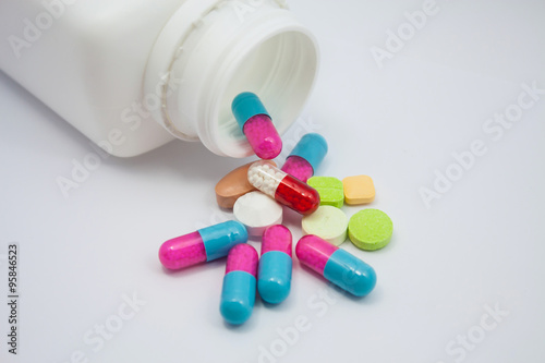 Colored pills, tablets and capsules on white background