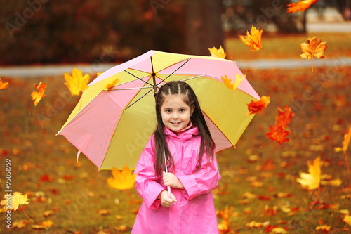 Beautiful little girl with umbrella in park