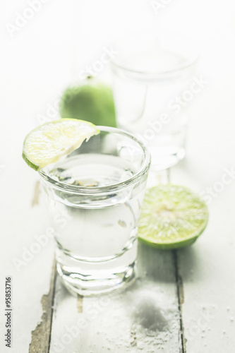 Vodka shot with lime and salt on wooden table background
