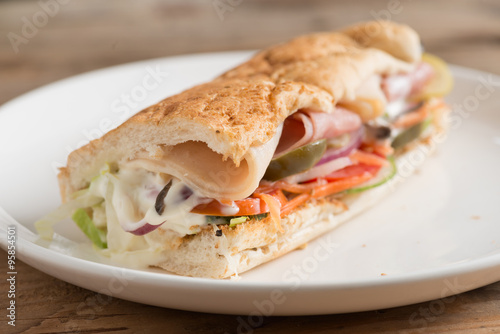 Long sandwich with ham, cheese, tomatoes, red onion and lettuce.
