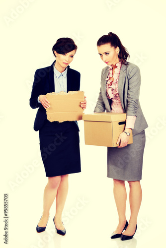 Two sad businesswoman carrying box. © Piotr Marcinski