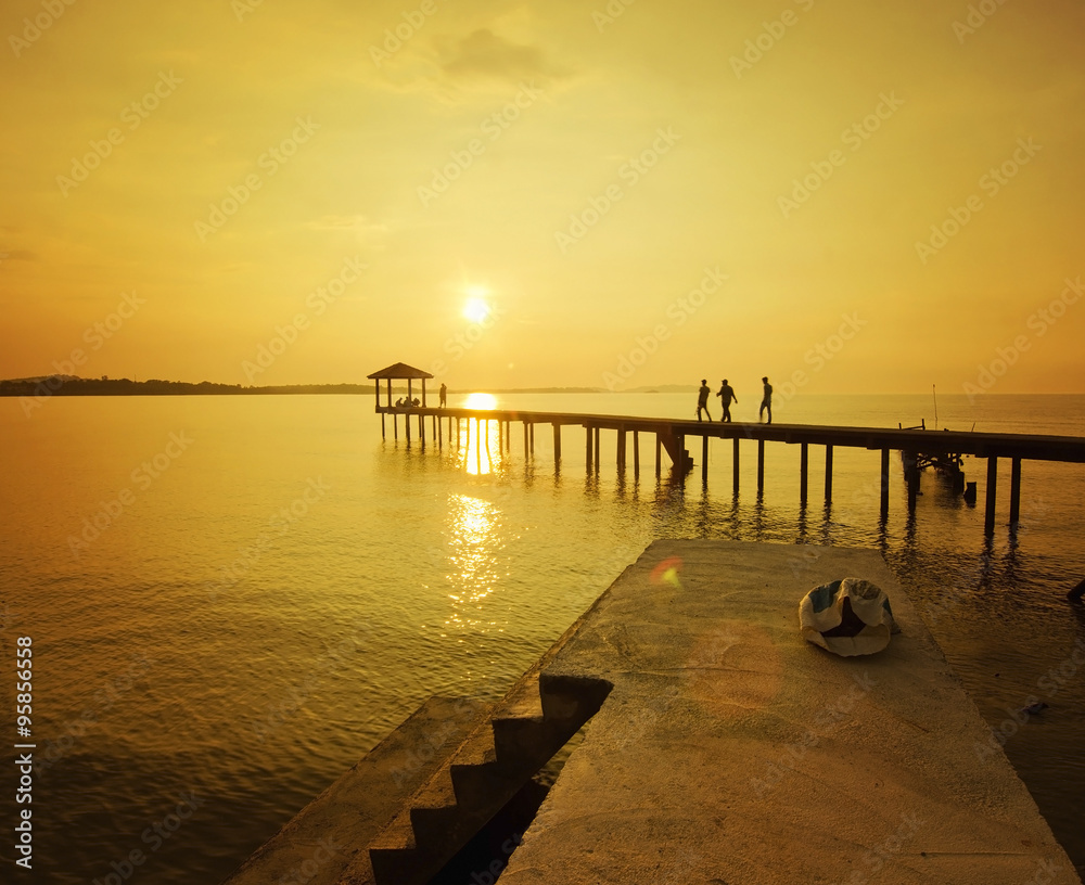 silhouette of man walking at the jetty during golden sunset