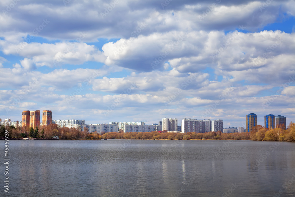 Amazing spring cityscape of Moscow on the river bank in the distance under beautiful cloudy sky with blue holes Amazing spring cityscape of Moscow on the river bank in the distance under beautiful cloudy sky with blue holes